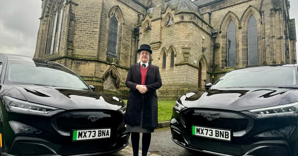 A Funeral Director with hearse and limousine outside a chapel